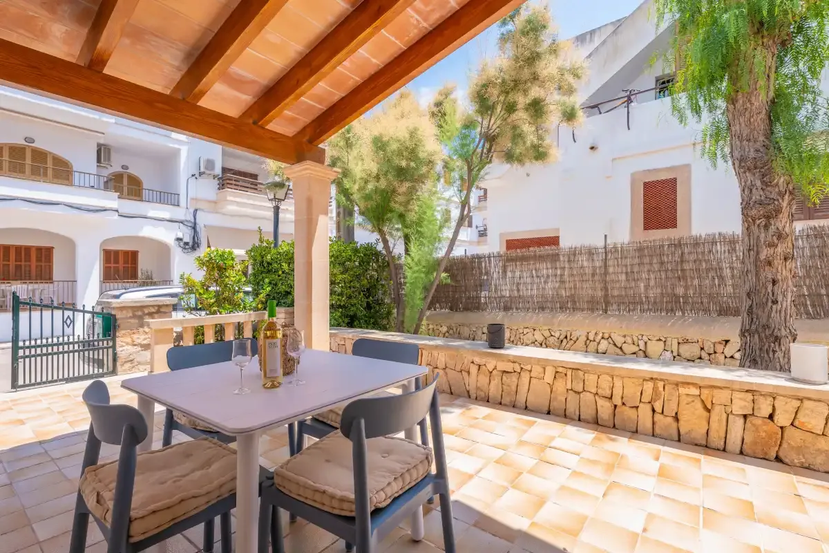 A covered outdoor patio with a dining table overlooks a planted courtyard.