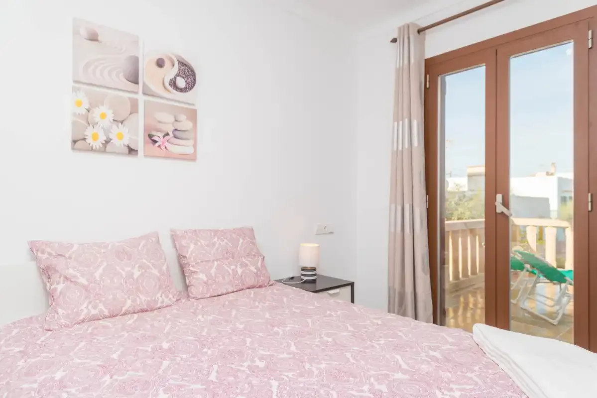A bedroom with pink bedding and glass doors opening onto a balcony.