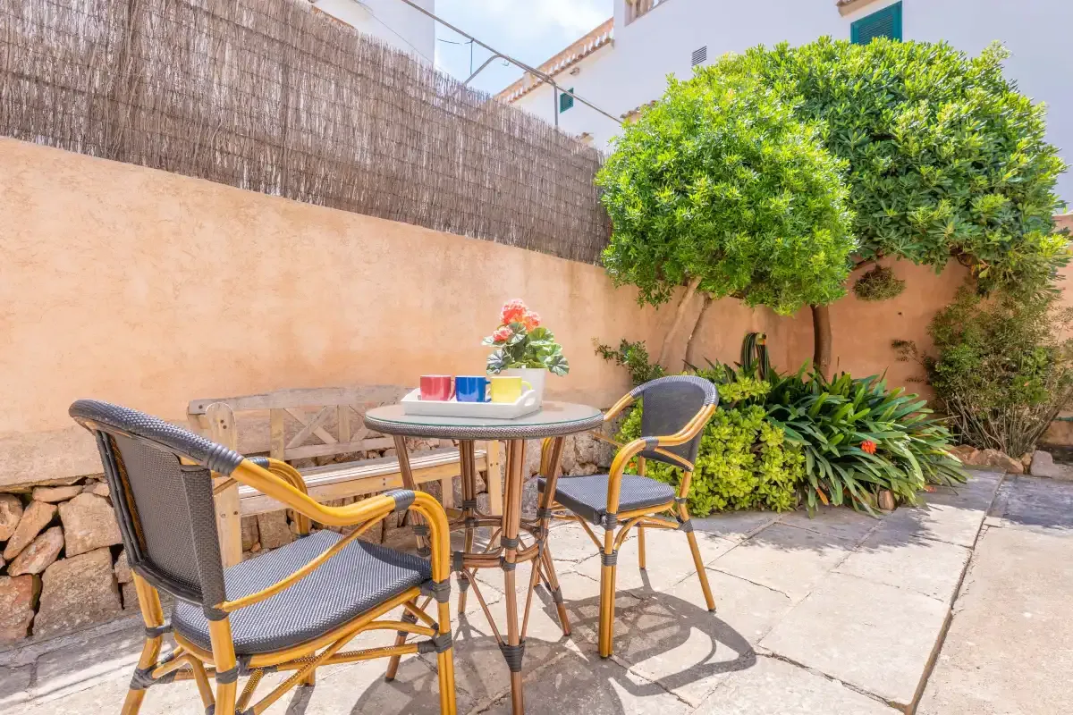 An outdoor patio seating area with a small table and greenery.