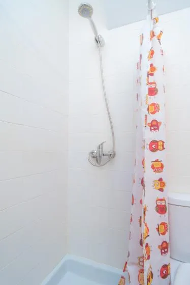 A tiled bathroom shower with a colorful patterned curtain.