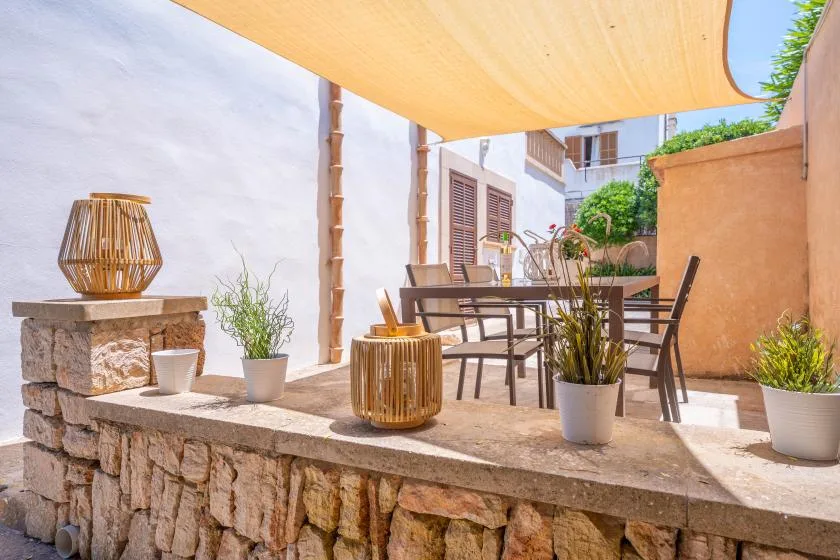 An outdoor patio dining area sits beneath a fabric shade canopy.