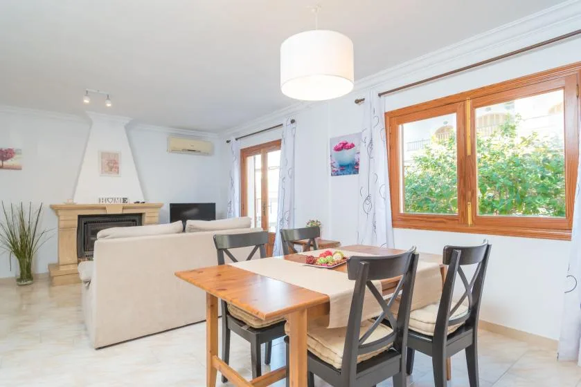A dining area with a wooden table and seating beside a large window.