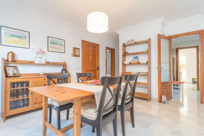 A dining area with a wooden table and several chairs beside shelving.