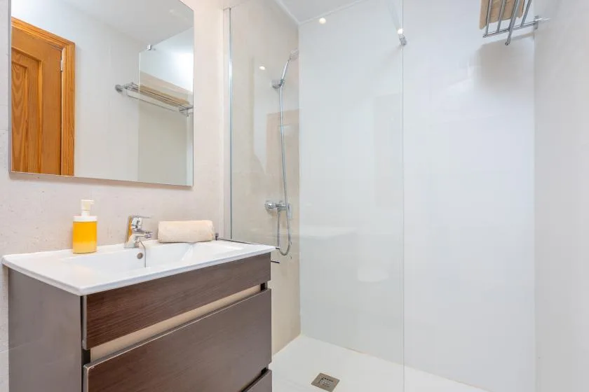 A bright bathroom with a sink vanity and a wall-mounted shower.