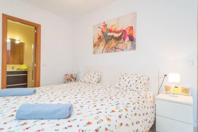 A bright bedroom with a large bed covered in patterned bedding.