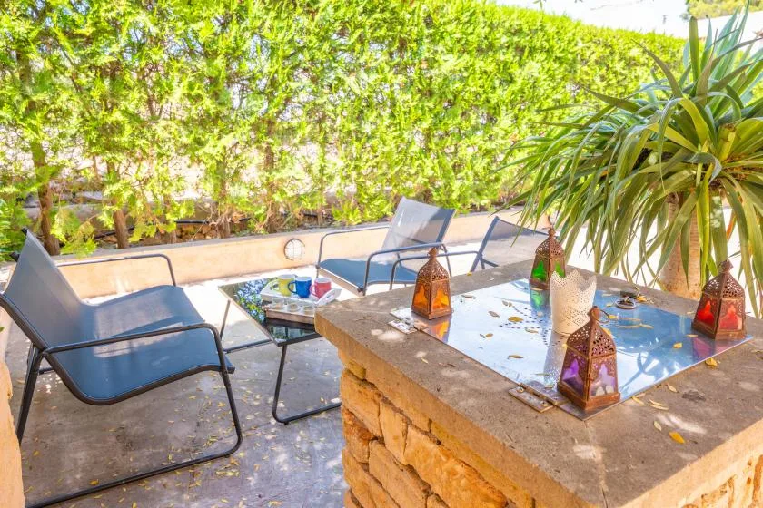 An outdoor patio has lounge seating around a stone table decorated with lanterns.