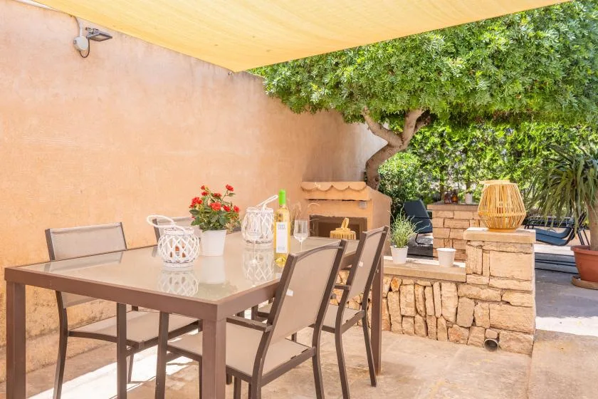 A shaded outdoor dining area with a table, chairs, and a stone counter.