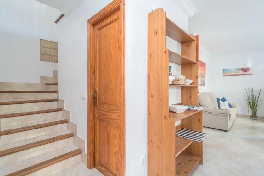 A bright living area with a wooden shelving unit beside the staircase.