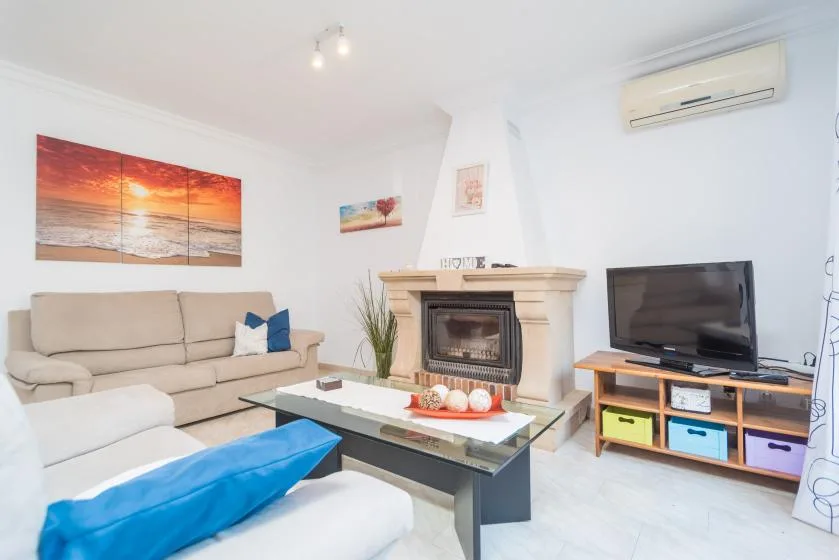 A bright living room with seating, a fireplace, and a television.