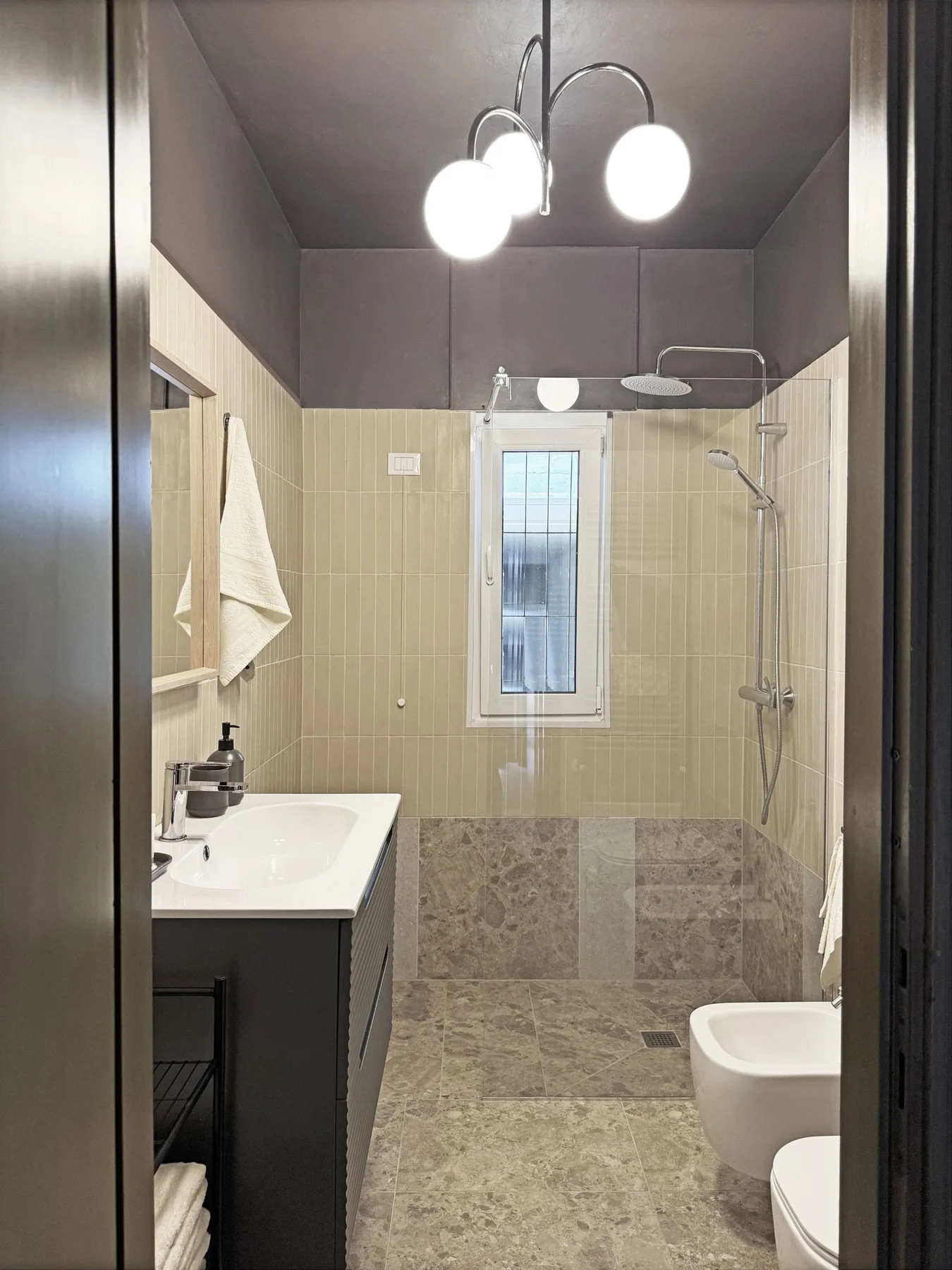 Un baño con azulejos, lavabo, ducha y ventana.