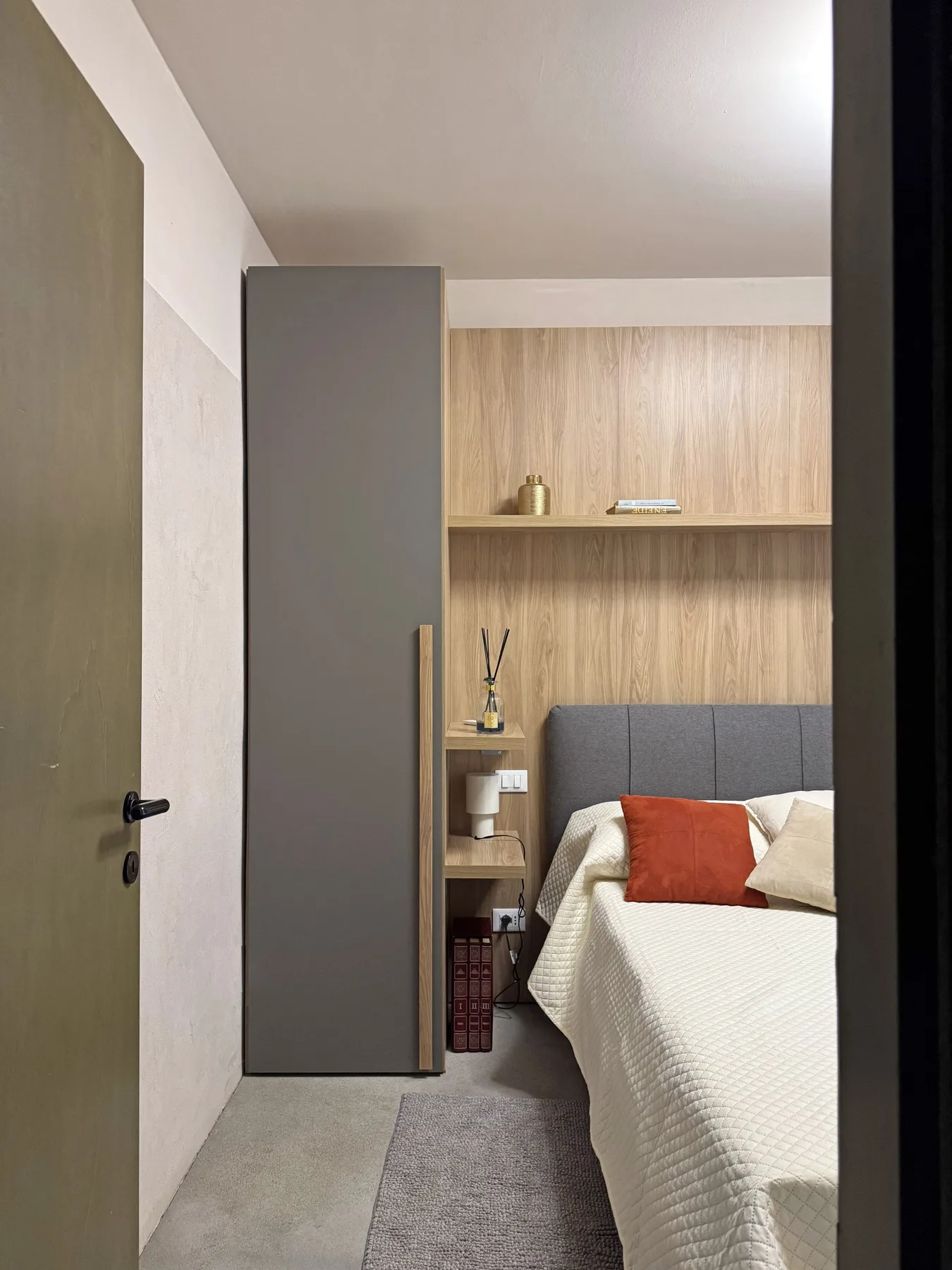 Dormitorio con una cama bien hecha y estanterías empotradas de madera.