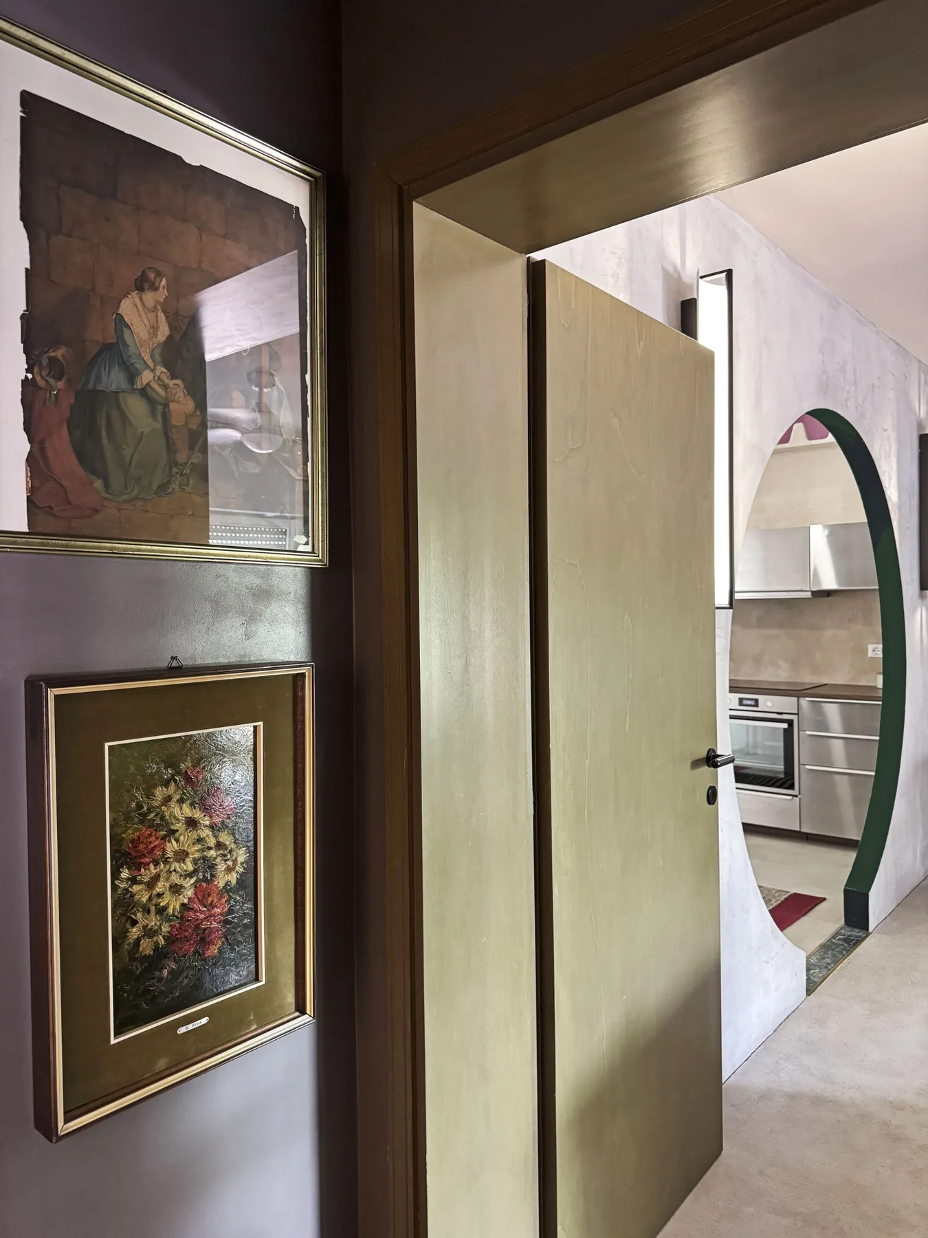 Una puerta da a una cocina, con cuadros colgados en la pared cercana.