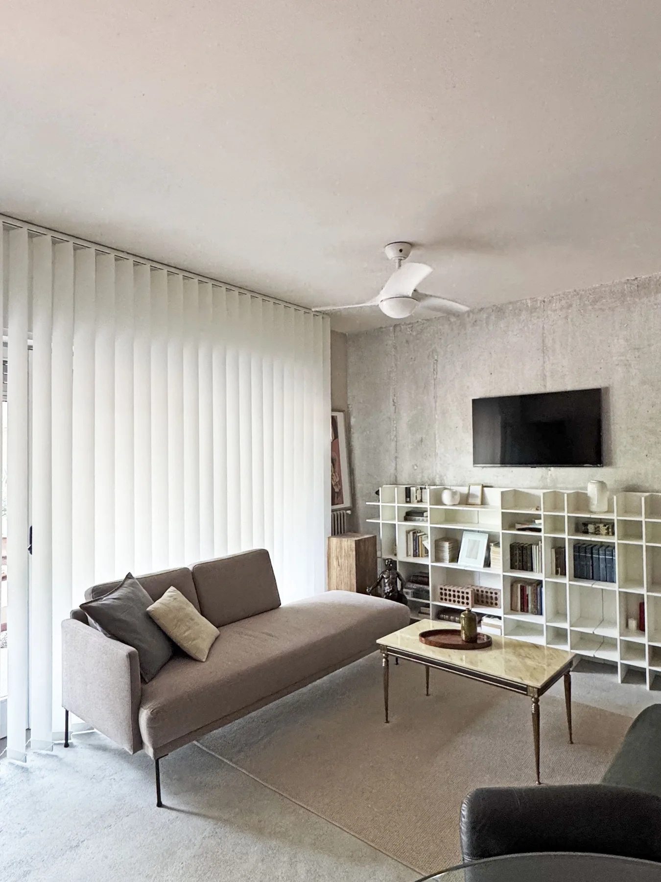 Una sala de estar con sofá, mesa de centro y televisor en la pared.