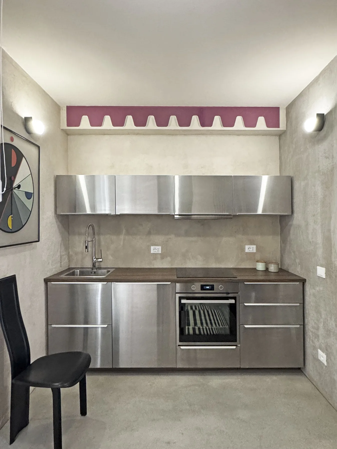 Una cocina compacta con gabinetes de acero inoxidable, fregadero y horno.