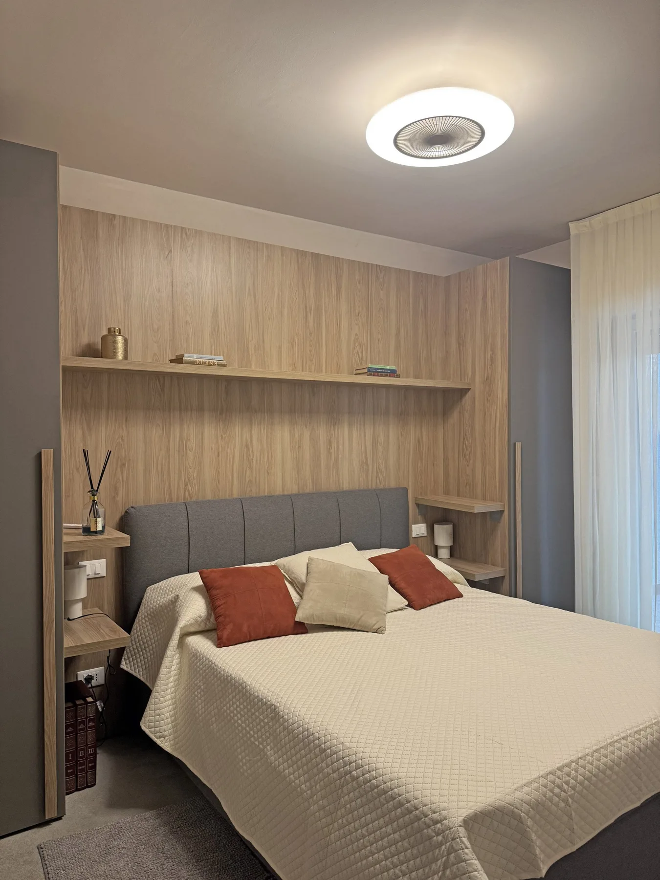 Un dormitorio con una cama bien tendida, mesitas de noche y una pared revestida de madera.