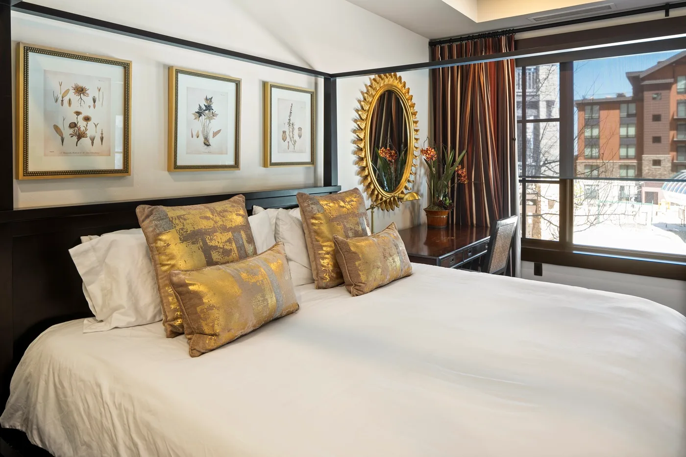 A bedroom with a neatly made bed and decorative pillows beside a large window.