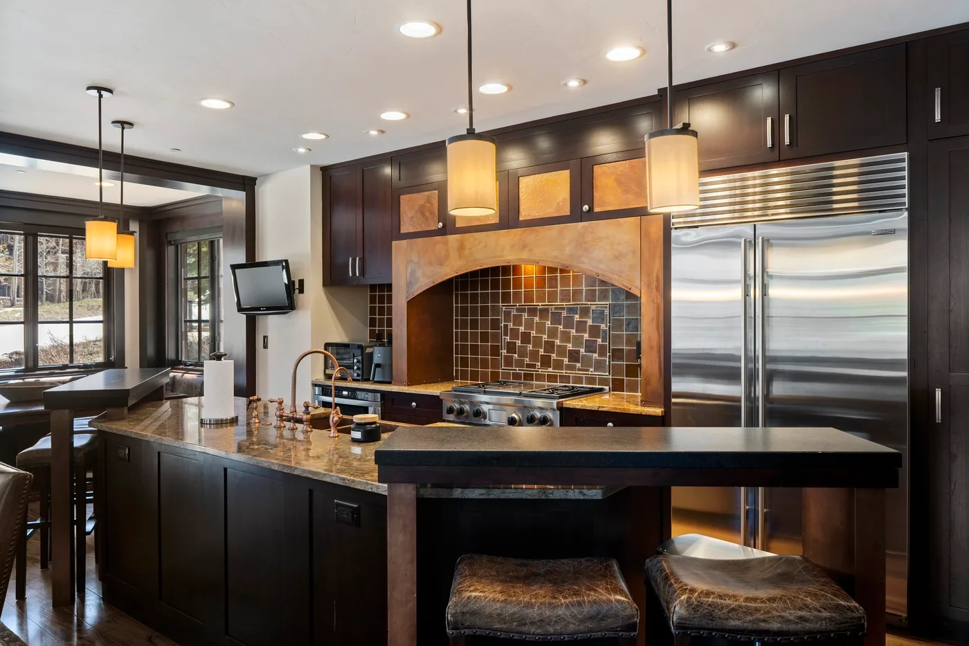 A modern kitchen with dark cabinetry, stainless steel appliances, and a large island.