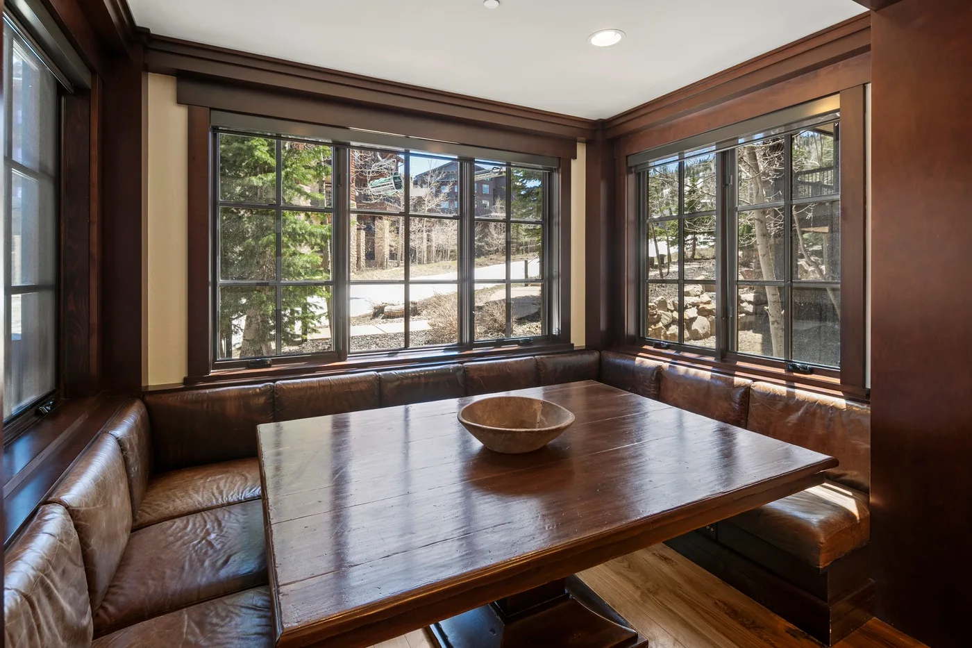 A window-lined sitting area with built-in seating and a wooden table.