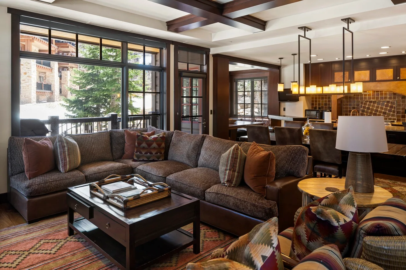 A living room with sectional seating, a coffee table, and an open kitchen.
