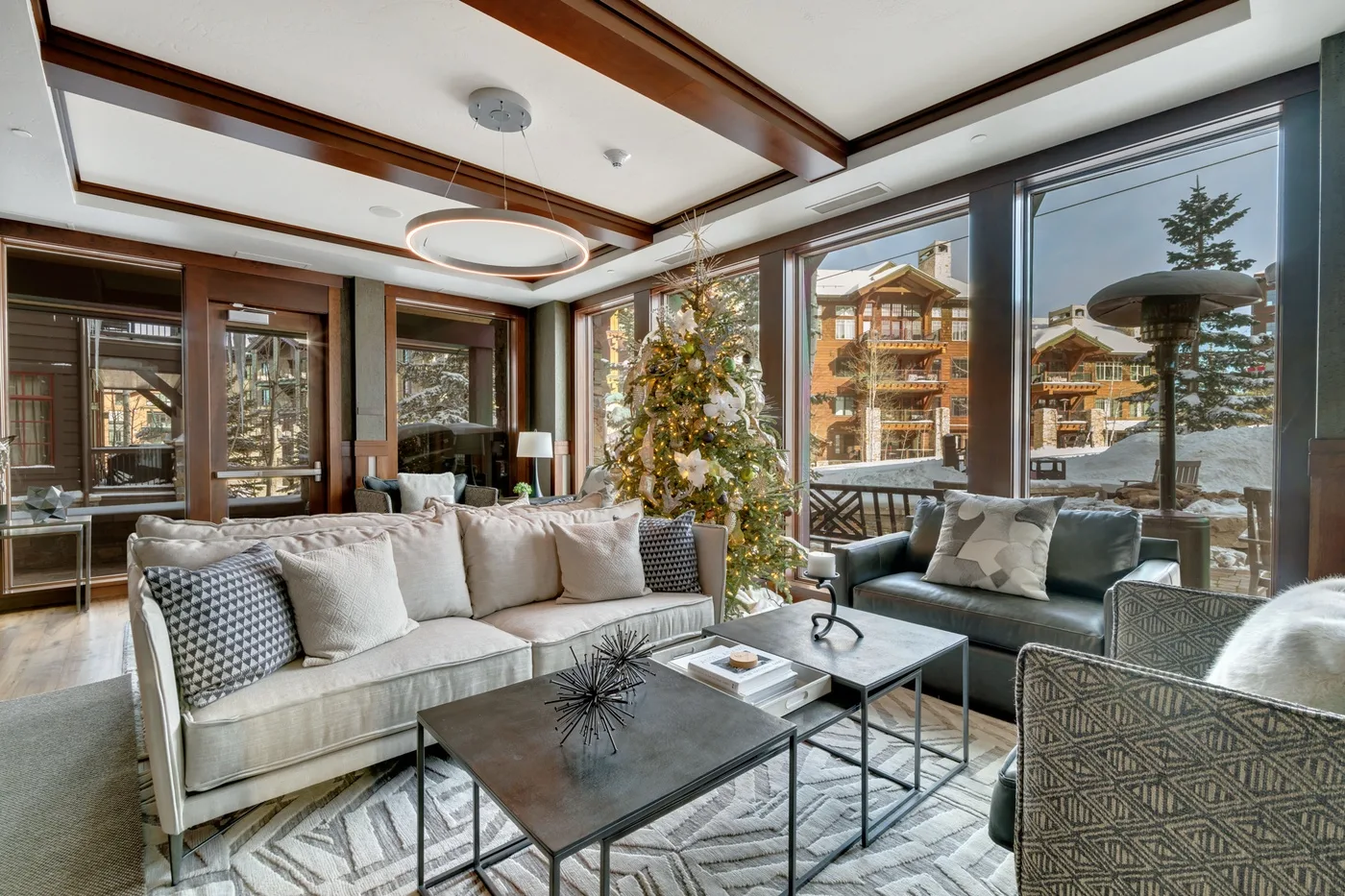 A bright living room with seating around low tables and a decorated Christmas tree.
