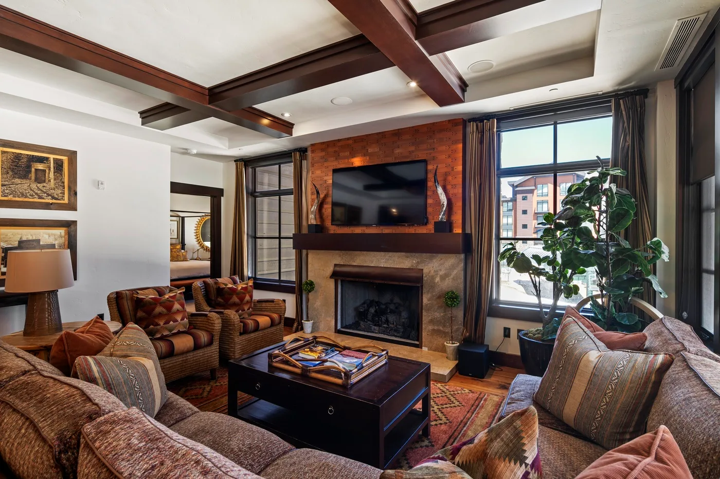 A living room with sofas, a coffee table, and a fireplace beneath a wall-mounted television.