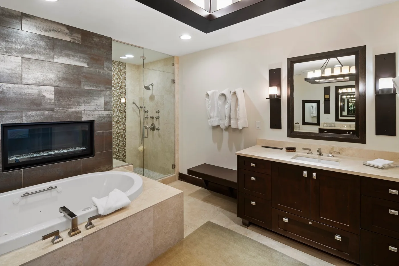 A spacious bathroom features a bathtub, glass shower, and dark wood vanity.