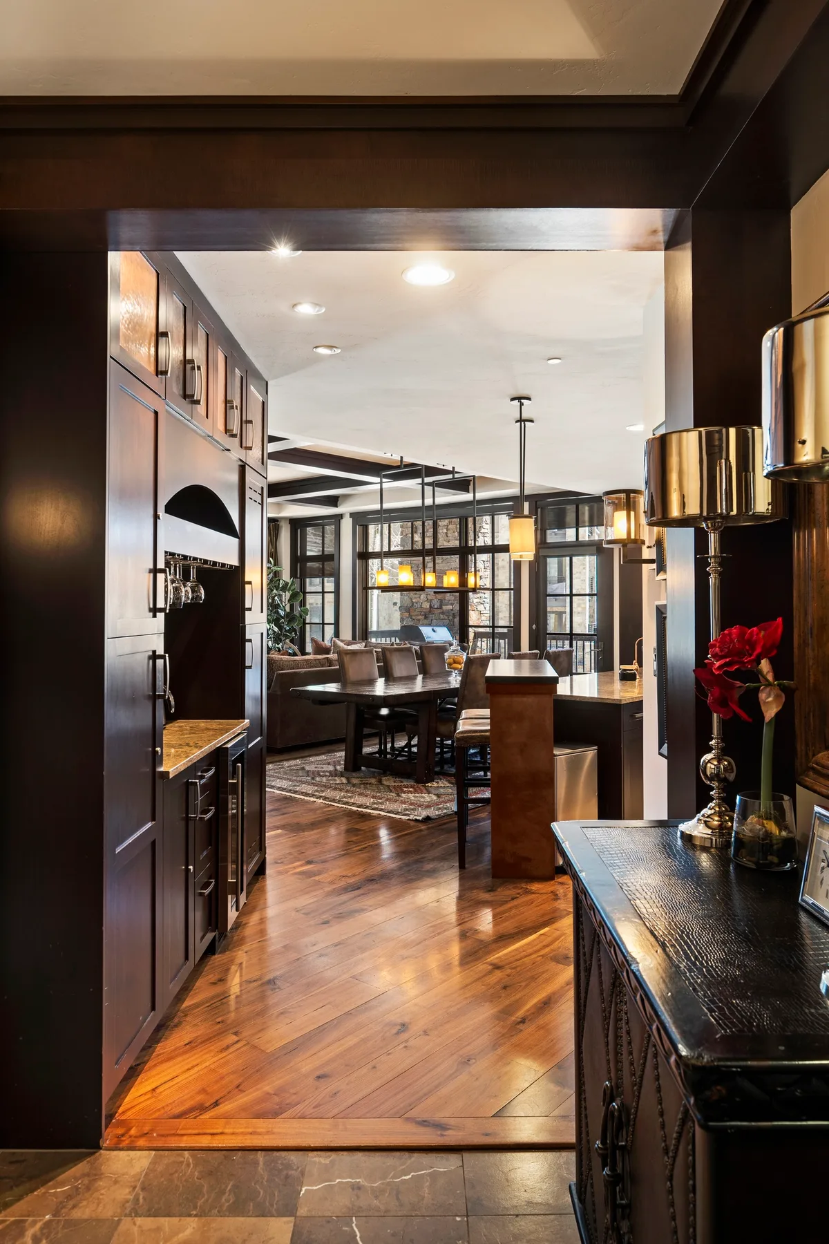 A warm, open-plan kitchen and dining area with dark cabinetry and wood floors.