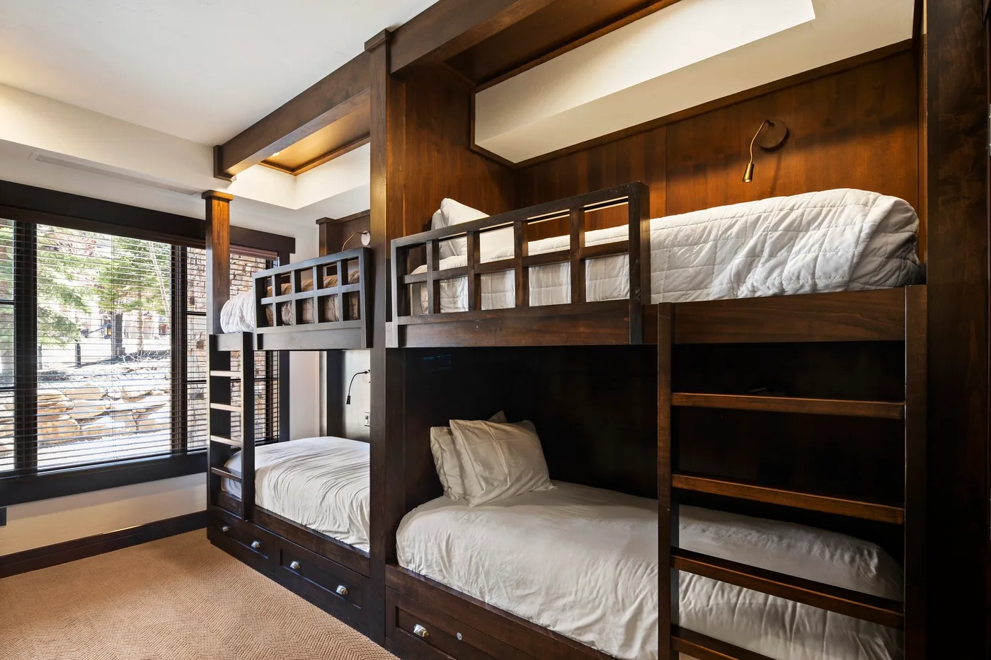 A bedroom with dark wooden bunk beds and white bedding.