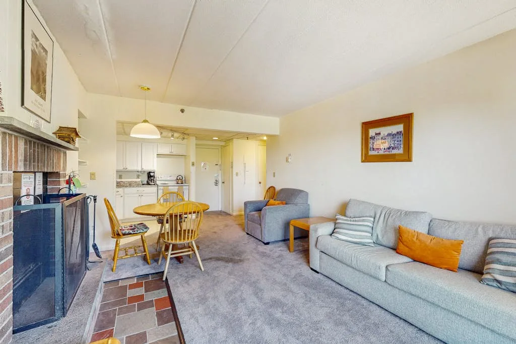 A living room with seating around a dining table and an open kitchen beyond.