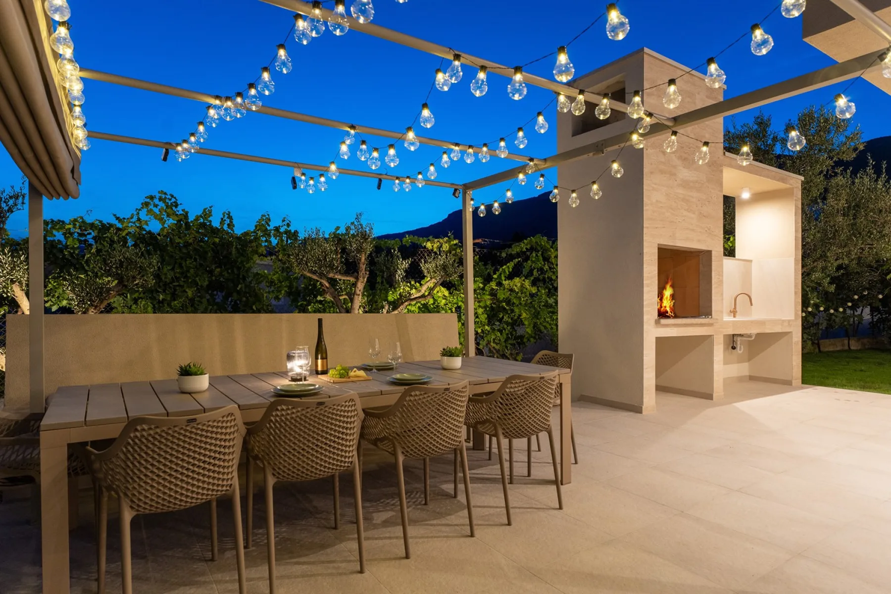Una zona de comedor al aire libre a la sombra con iluminación ambiental.