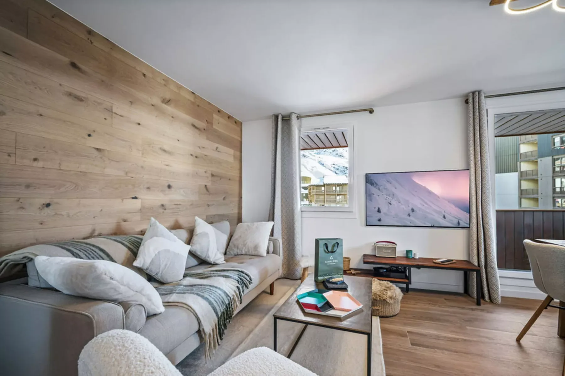 A living room with a sectional seating area, coffee table, and wall-mounted screen.
