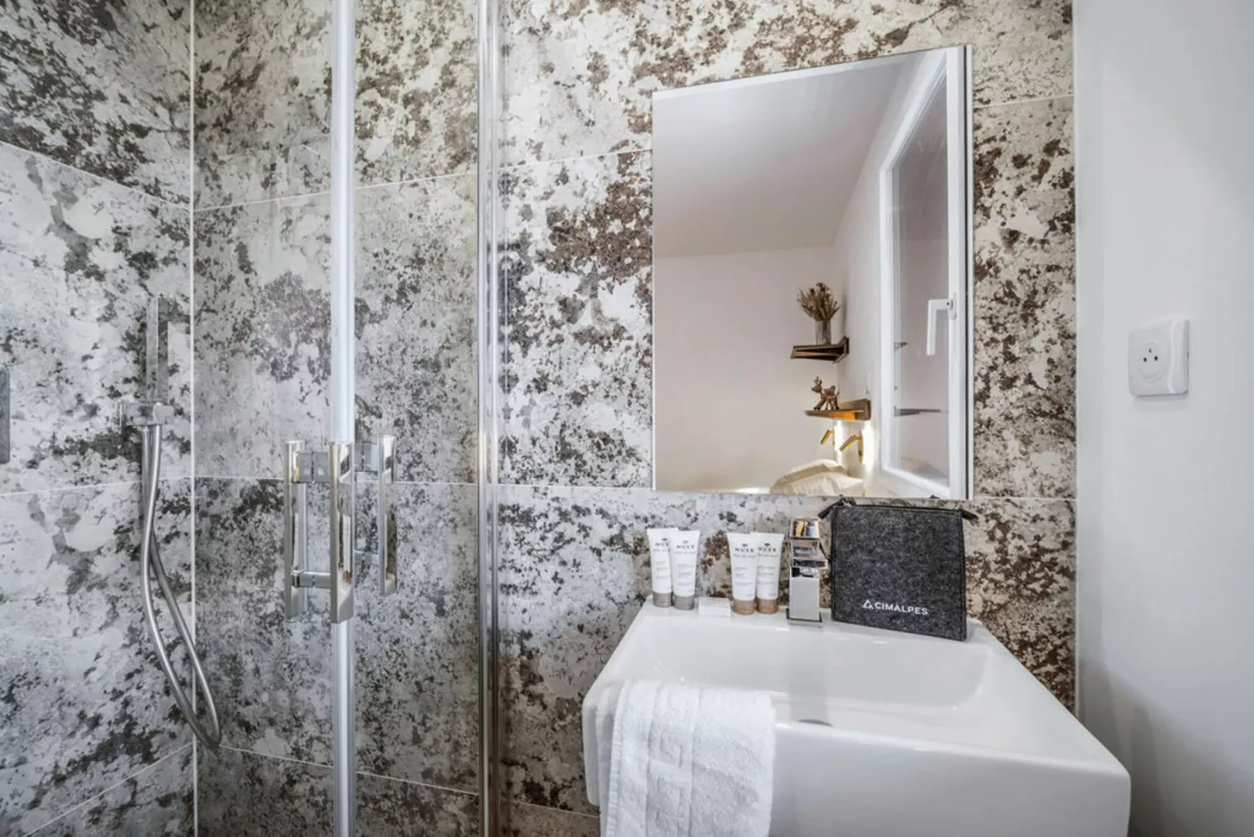 A bathroom with a glass shower, sink, and mirror.