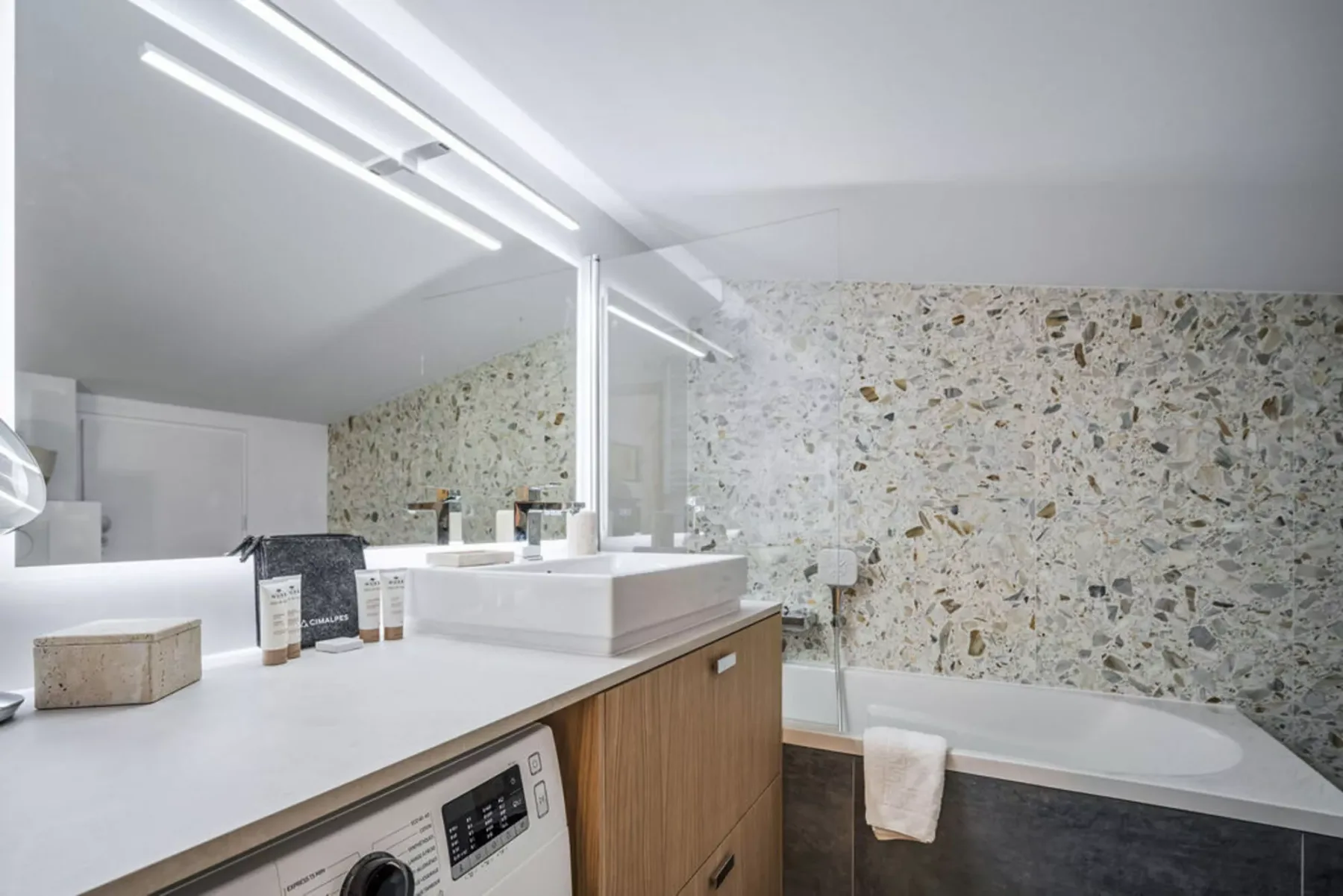 A bathroom vanity with a sink and mirror sits beside a bathtub.