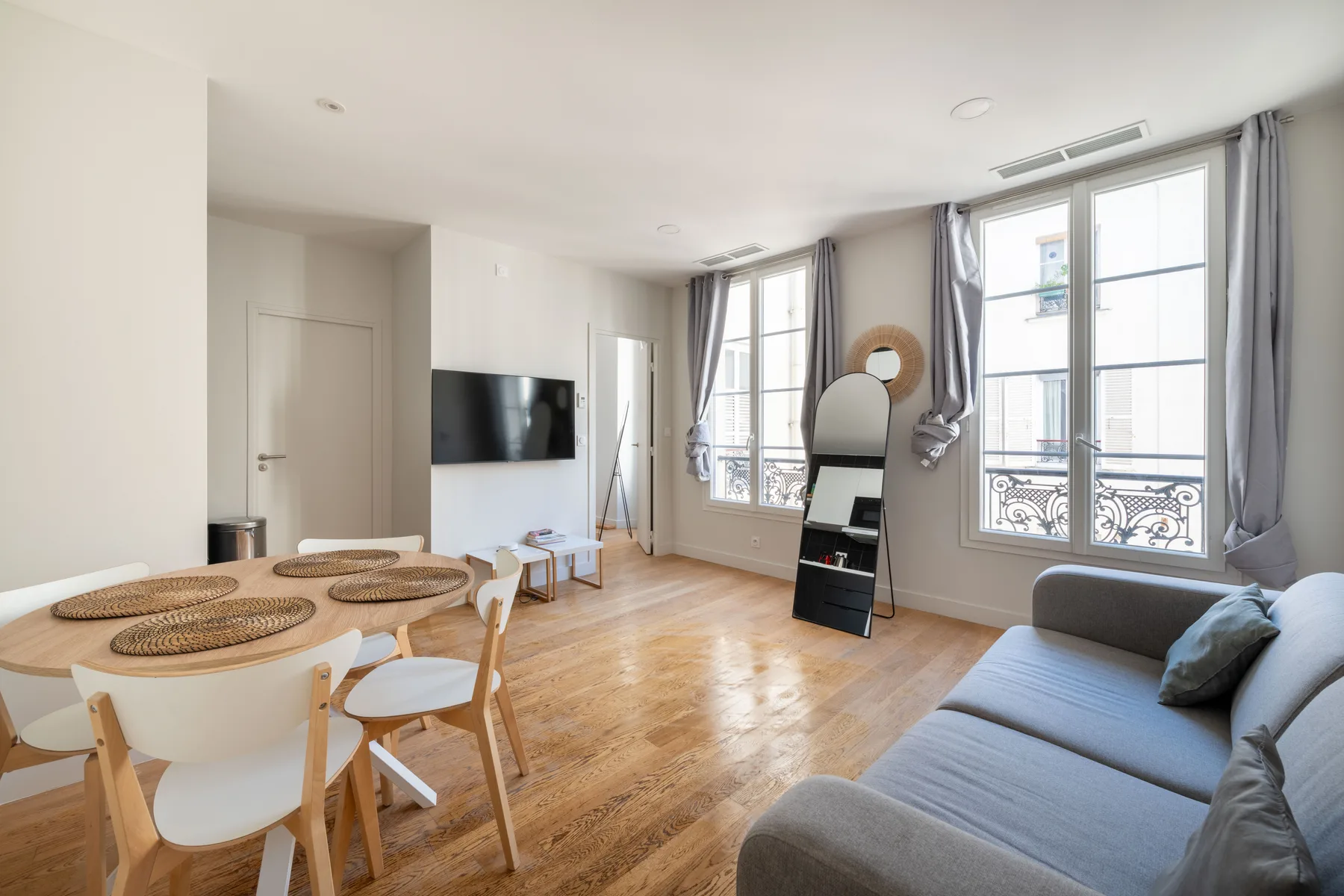 A bright living and dining area with large windows and a television.