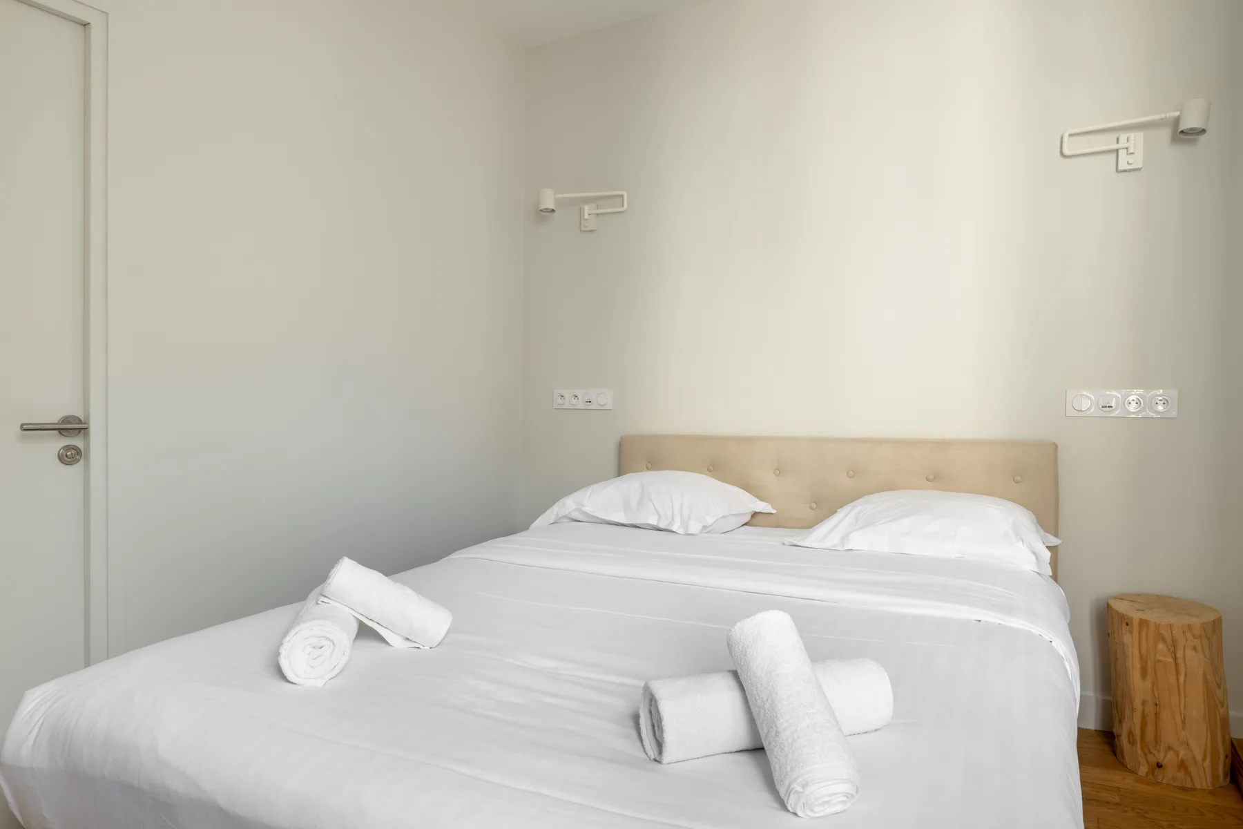 A bedroom with a neatly made bed and rolled towels.