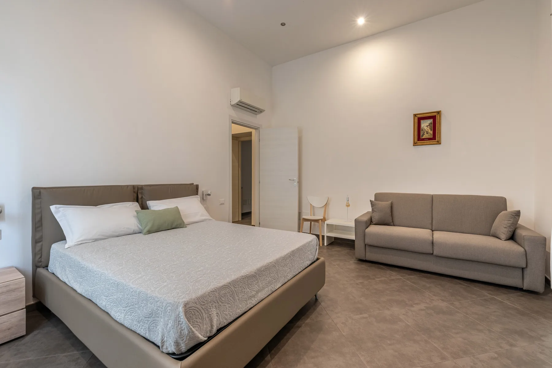 A bedroom with a large bed and a sofa against the wall.