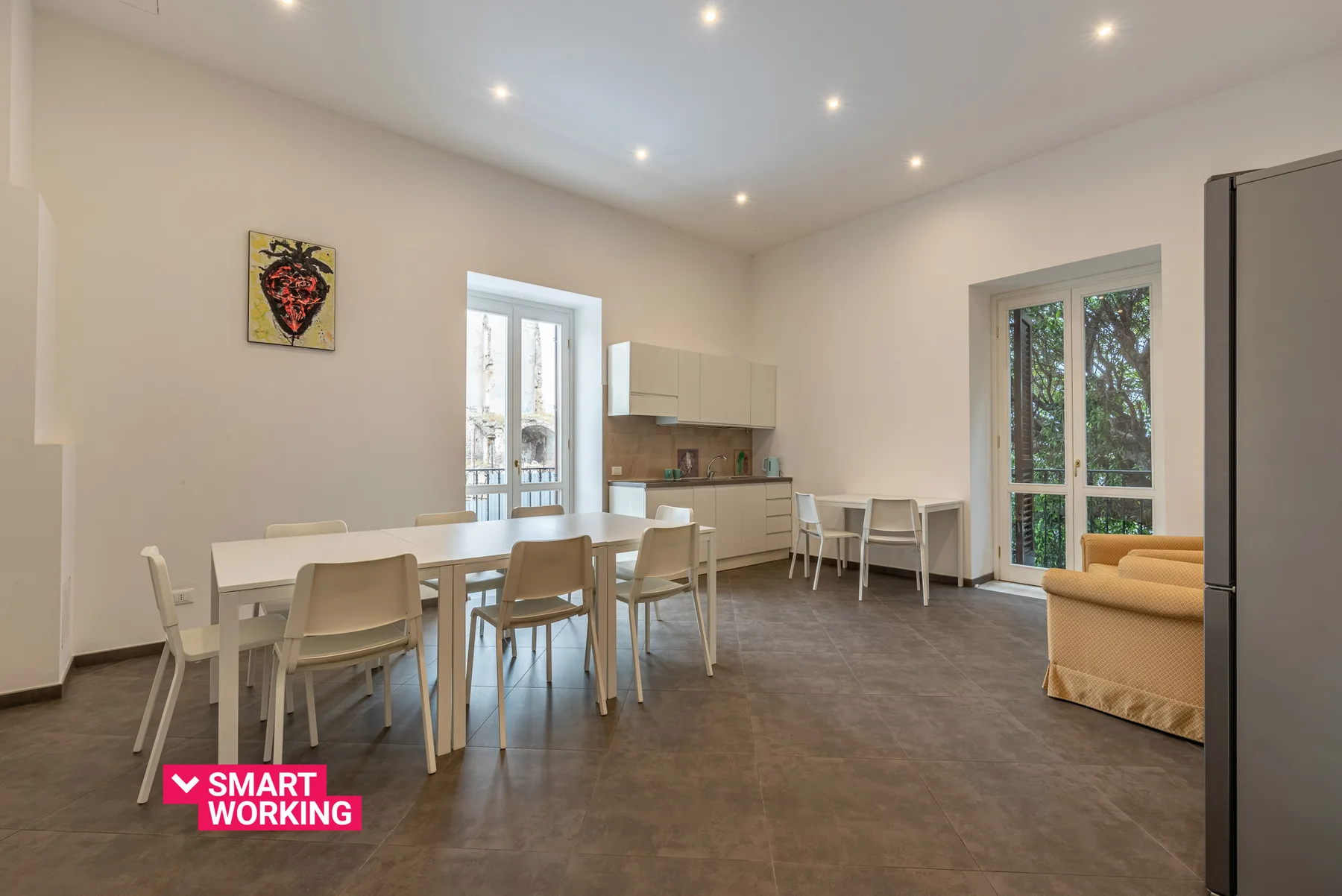A bright dining and kitchen area with a long table and large windows.