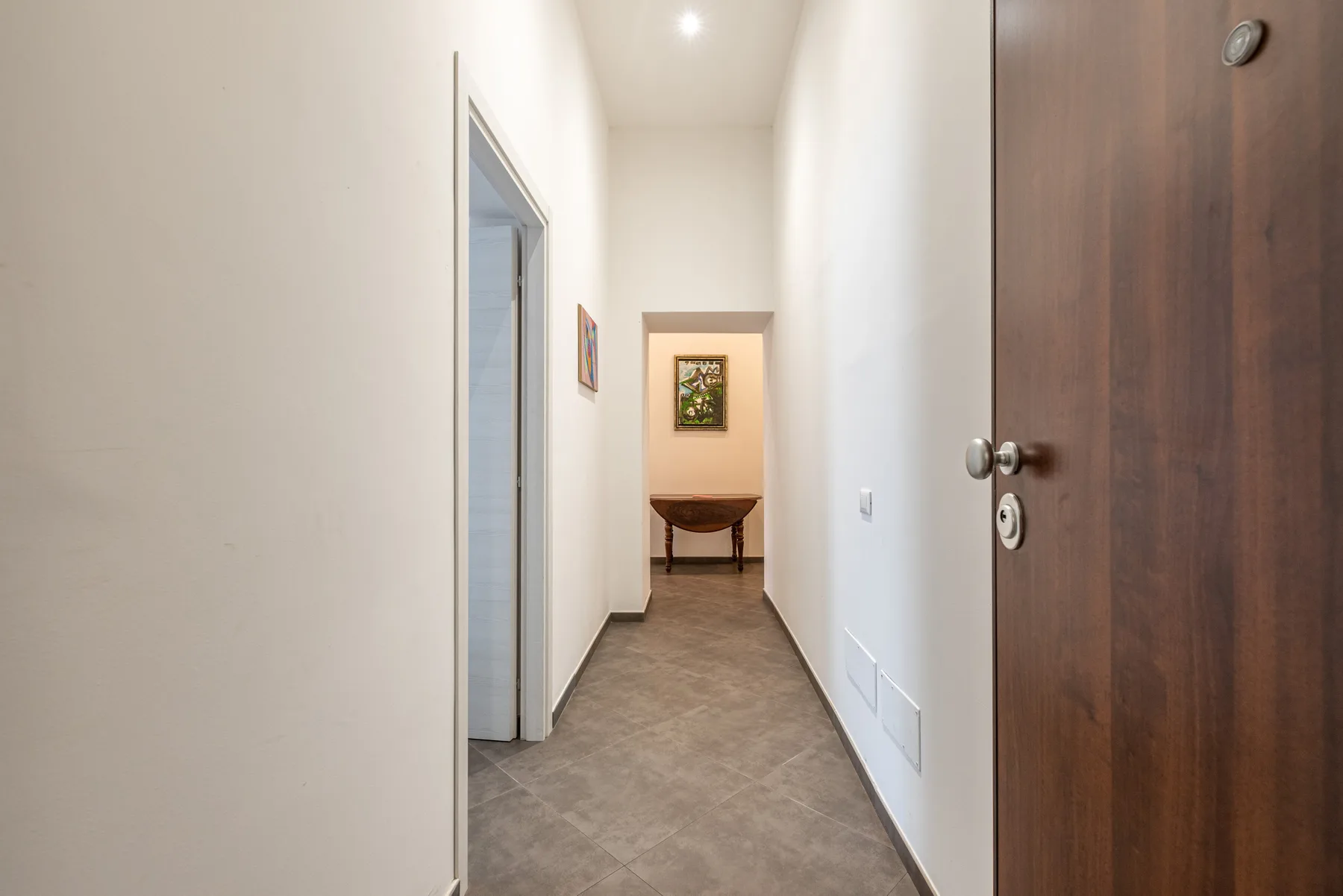 A bright hallway leads to a small seating area with framed artwork.