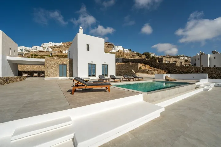 A modern white villa opens onto a terrace with a swimming pool.
