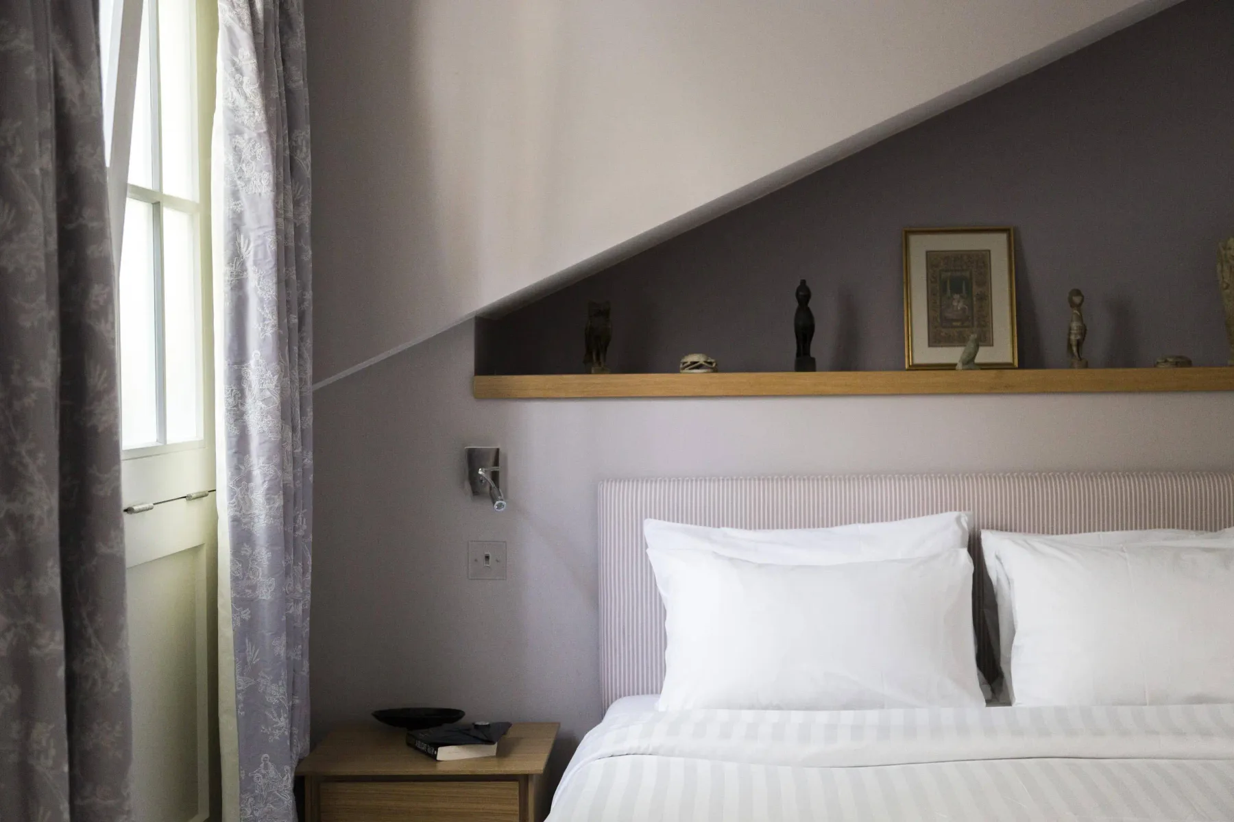 A bedroom with a white bed beneath a sloped ceiling.