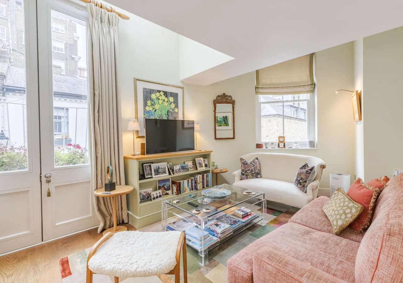 A bright living room with seating, a television, and large windows.