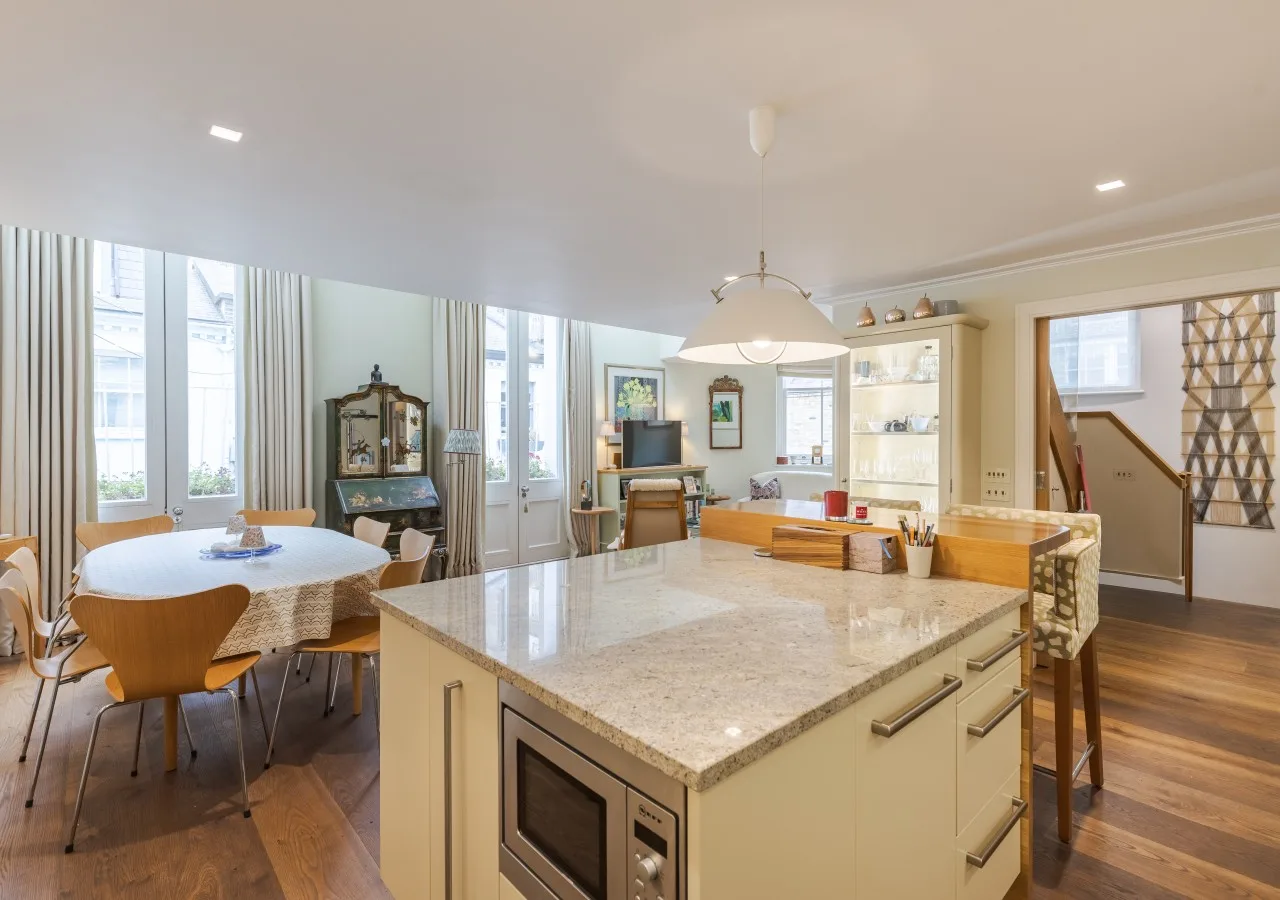 An open kitchen and dining area with a large central island and round table.