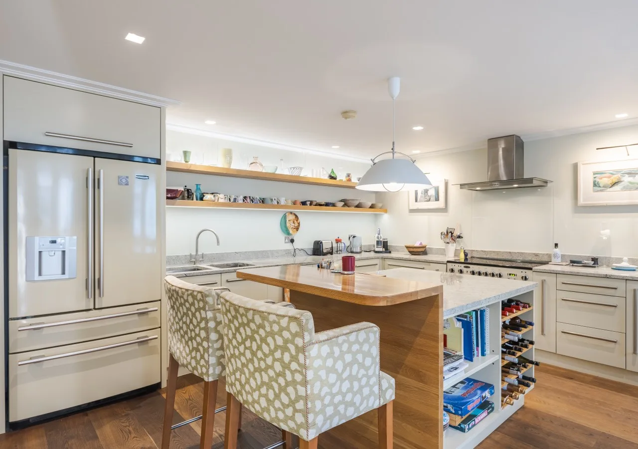 A bright kitchen with a central island, counter seating, and stainless steel appliances.