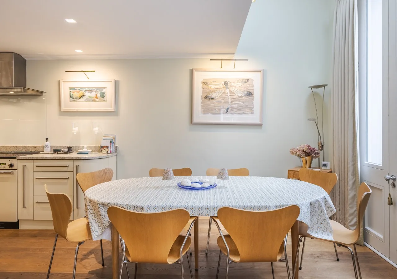 A dining area with a round table set with dishes beside the kitchen.