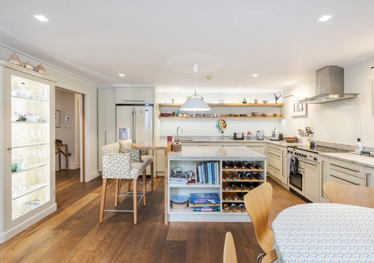 A bright kitchen and dining area with a central island and wooden flooring.