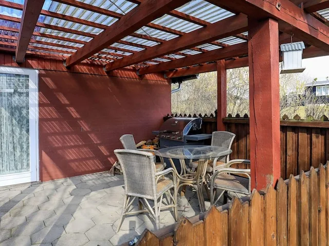Patio cubierto con asientos al aire libre y una parrilla.