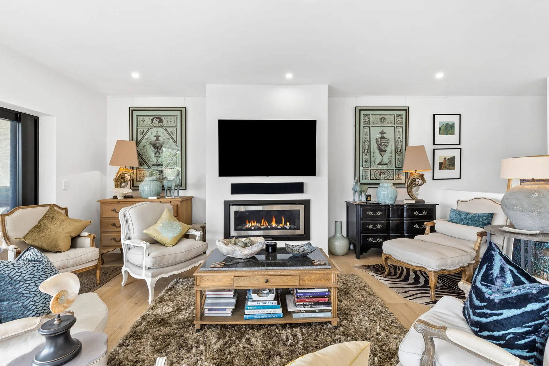 A bright living room with seating arranged around a television and fireplace.