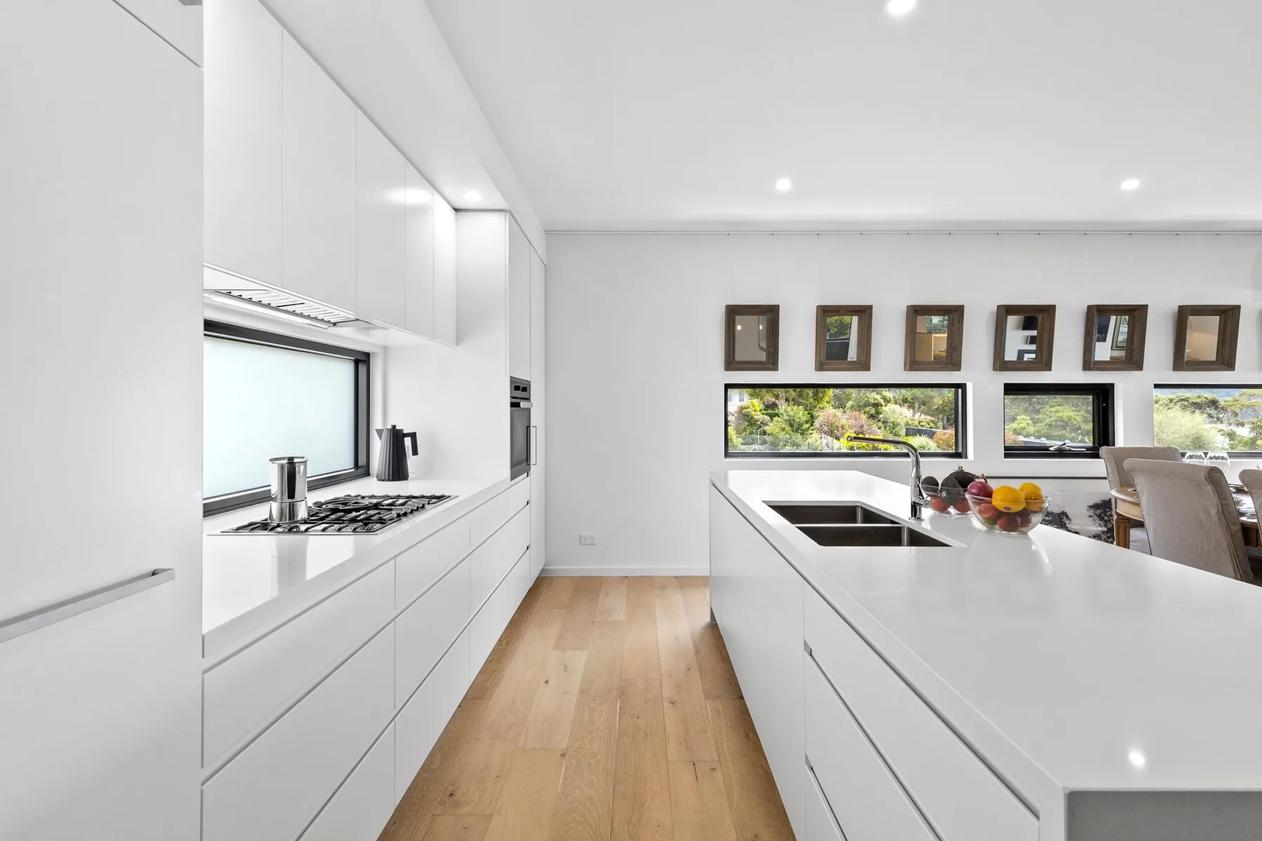 A bright kitchen with white cabinetry, a central island, and windows overlooking greenery.