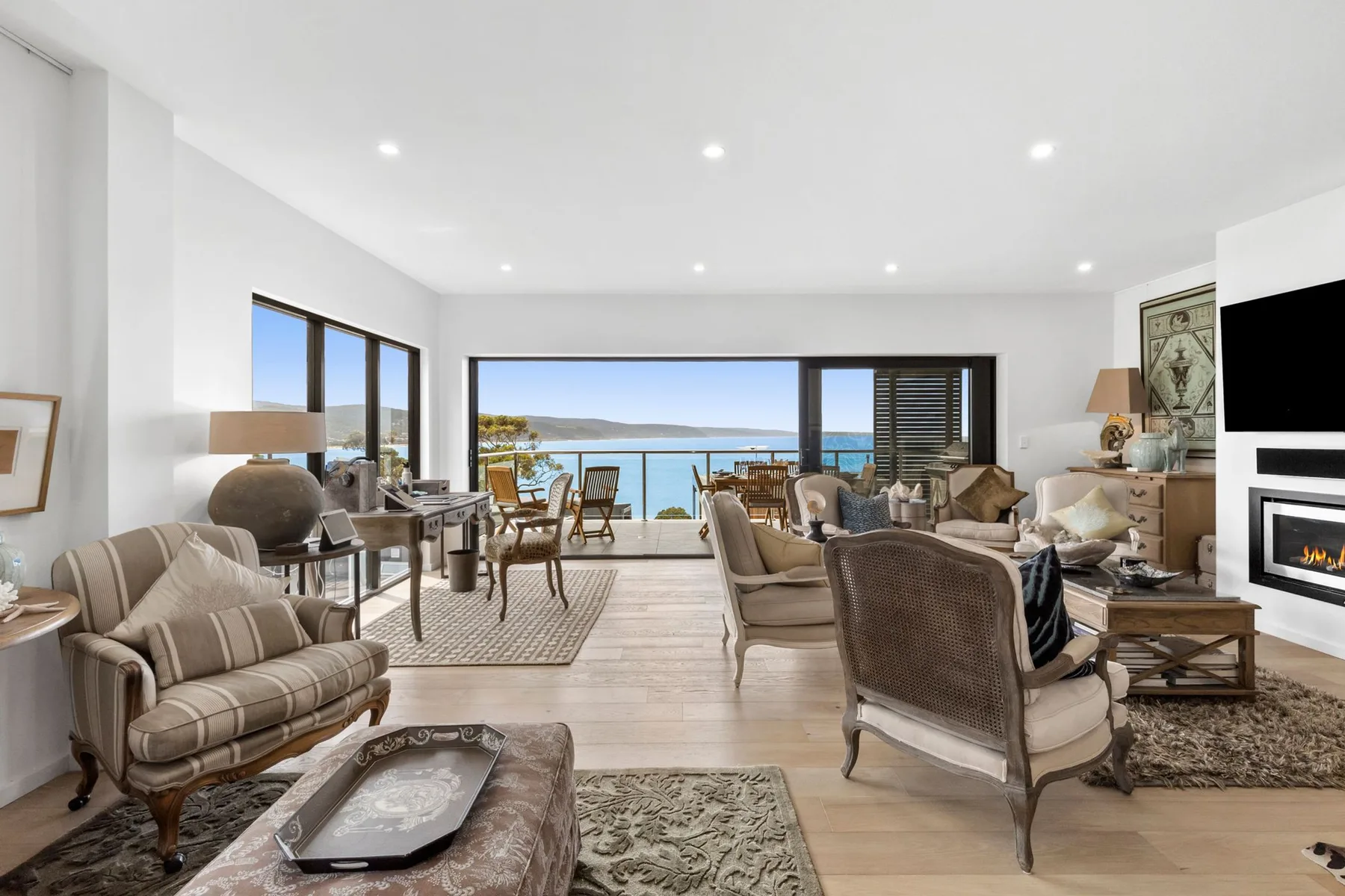 A bright living room opens onto a balcony with ocean views.