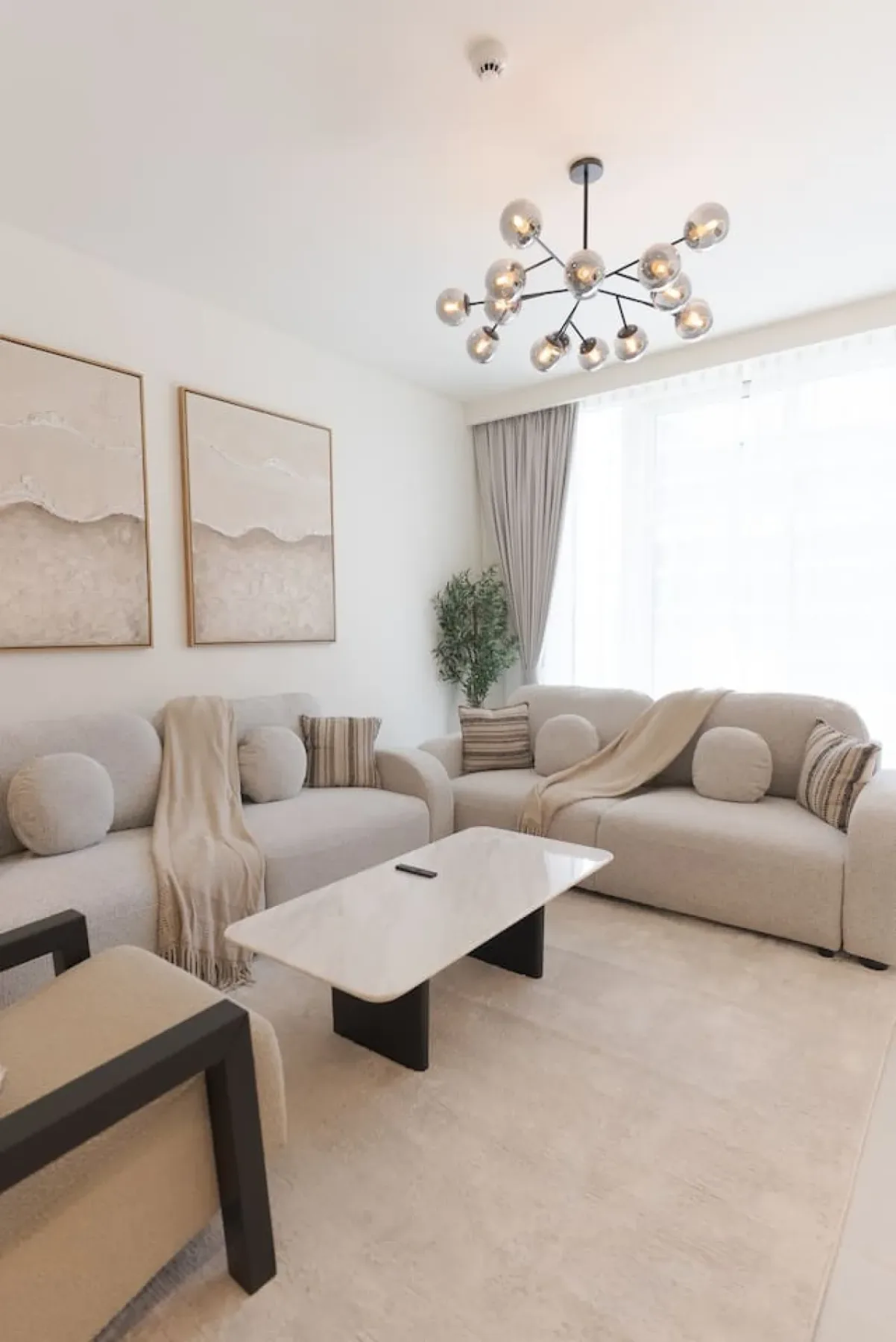 Una sala de estar luminosa con asientos claros y una mesa de centro blanca.